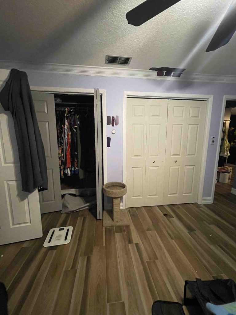 Image of the before, main bedroom closet view with a small wall in-between two bifold doors
