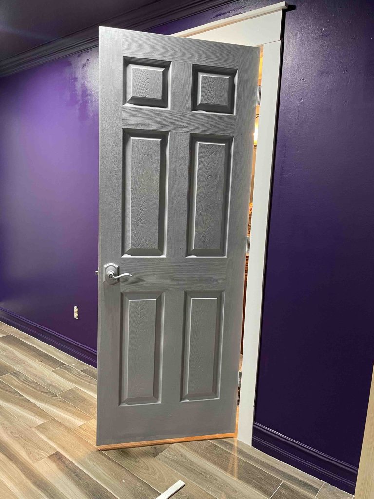 Image of freshly painted bedroom wall with EZ roller. The color is Eminent purple. The door is only primed gray , not painted