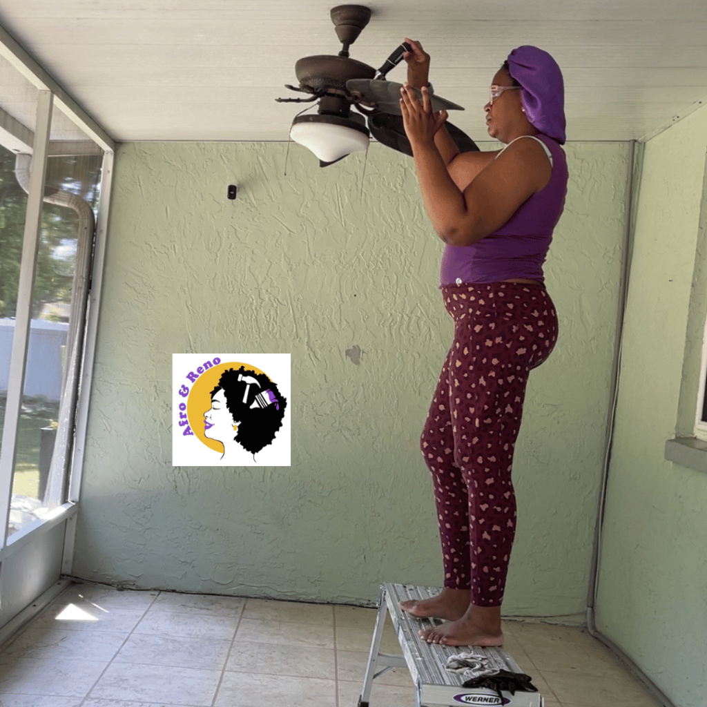 DIY patio refresh prep. Tamarah @afroandreno is taking down the fan blades from a ceiling fan while standing on a platform