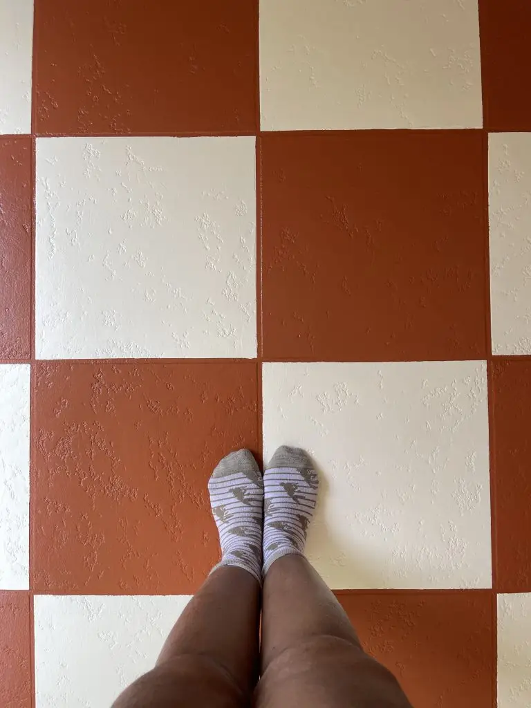 Image of Afro and Reno standing on top of a finished checkerboard floor. The base color is off white and the alternating color is a terracotta orange